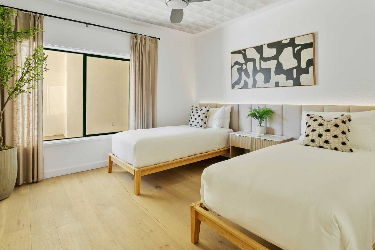 A modern bedroom with a large bed featuring white linens and patterned pillows