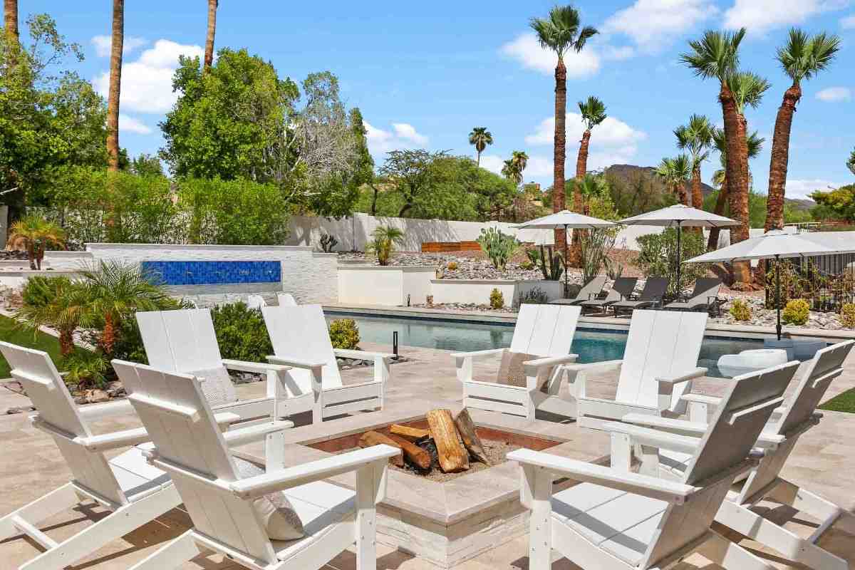 Spacious backyard with a central fire pit surrounded by white chairs