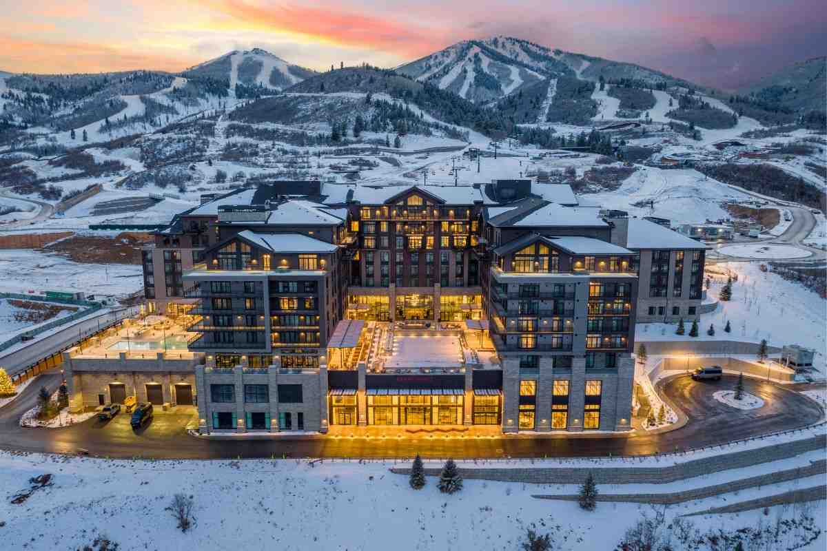 A luxurious, warmly lit mountain resort nestled in snowy terrain with ski slopes visible behind