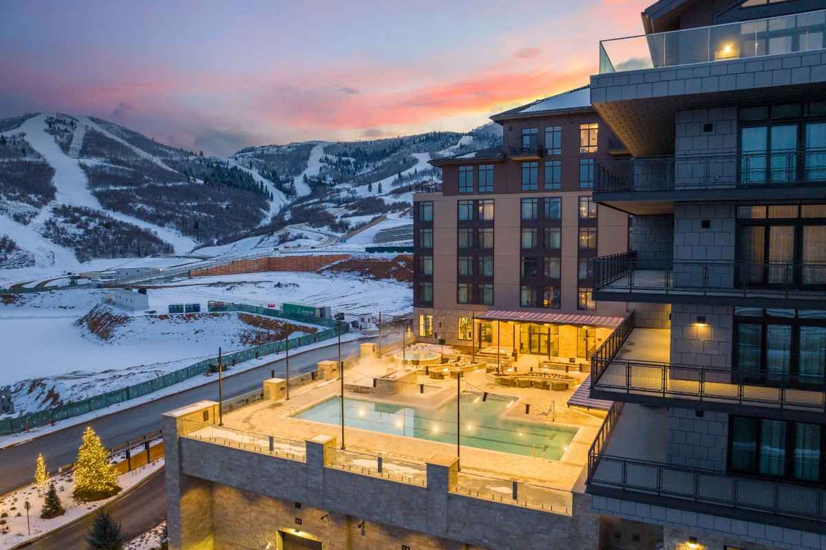 A snow-covered luxury hotel glows warmly at dusk