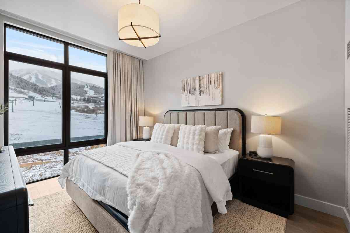 Modern bedroom with a large window showing a snowy mountain view